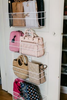 a white closet with several baskets and purses hanging on the wall next to it