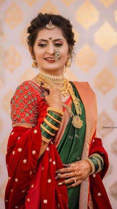 a woman in red and green sari with gold jewelry on her face, posing for the