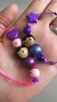 a person's hand holding several small wooden beads with purple, blue and pink colors