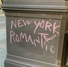 a chalkboard with the words new york romantic written on it in pink ink next to a sidewalk