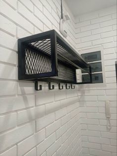 a bathroom with white brick walls and black metal shelfs on the wall above it