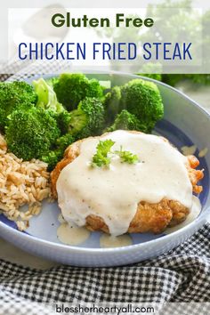 a blue plate topped with meat covered in gravy next to rice and broccoli