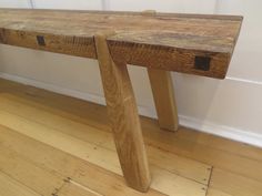 a wooden bench sitting on top of a hard wood floor next to a white wall