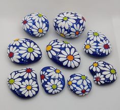 six painted rocks with daisies on them