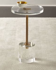 a glass table with a gold plate on it and a white rug in the background