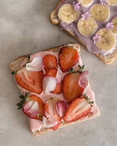 two slices of toast with strawberries and bananas on them, one is sliced in half