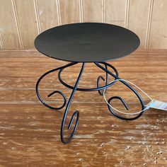 a small black table sitting on top of a wooden floor next to a painting brush