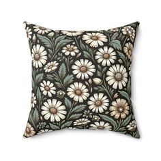 a black pillow with white daisies and green leaves on the front, against a white background