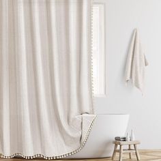 a bathroom with a white shower curtain and wooden flooring