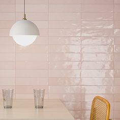 two chairs and a table in front of a pink wall with white tiles on it