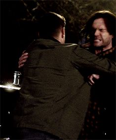 two men hugging each other in the dark