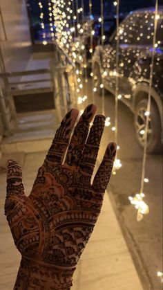 a henna on someone's hand with lights in the background