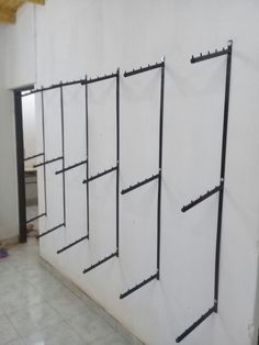 the wall is lined up with several black metal racks on it, along with two white walls and tile flooring