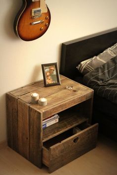 a wooden table with two drawers and a guitar hanging on the wall next to it