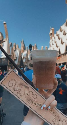 a person holding up a drink in front of a castle