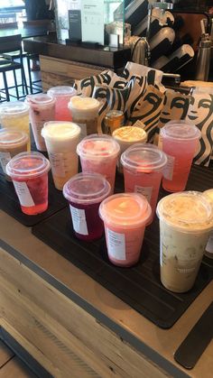 many cups of drinks are lined up on a tray in front of the counter at a coffee shop