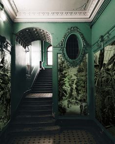 the hallway is decorated in green and white with an elaborate mirror on the wall above it