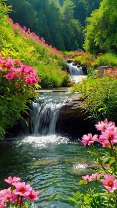 a small waterfall surrounded by pink flowers and greenery