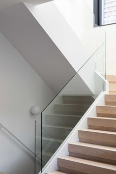 Wood stairs with a glass railing connect the various levels of this modern home. Stained Oak Cabinets, Luxury Staircase Design, Home Staircase Design, White Oak Staircase, Glass Stairs Design, Home Staircase, Glass Handrail