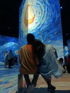 two people are sitting on a bench in front of a starry sky mural at the museum