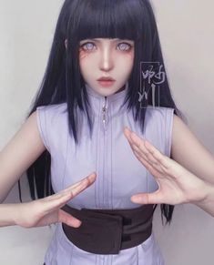 a woman with long black hair and bangs holding her hands in front of her face