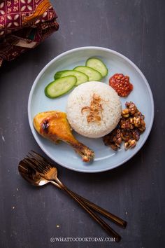 a white plate topped with rice, cucumbers and other food on top of a table