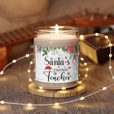 a lit candle sitting on top of a wooden table next to a string of lights