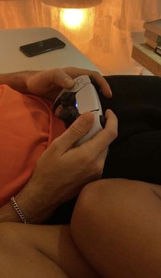 a person sitting on a couch holding a cell phone in their hand and looking at the screen