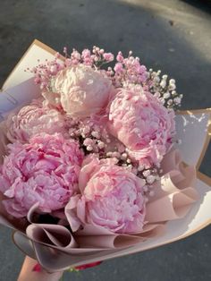 a bouquet of pink peonies and baby's breath in someones hand