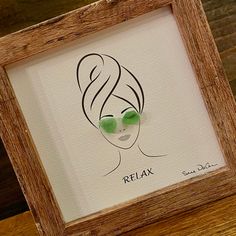 a drawing of a woman's face with green eyes in a wooden frame on a table