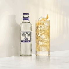 a bottle of london dry gin next to a glass filled with ice and lemonade