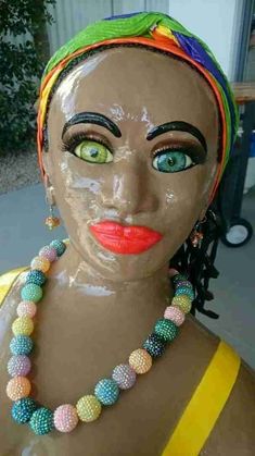 a mannequin head with colorful beads on it's face and green eyes