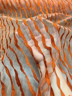 an orange and white fabric with wavy lines on it's sides, as well as the top part of another material