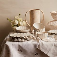 a table topped with white dishes and vases