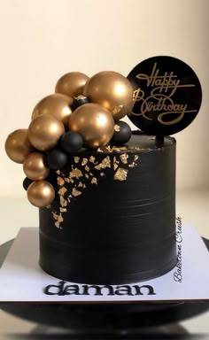 a black and gold birthday cake with balloons on top is shown in front of a white background