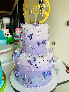 a three tiered cake with purple butterflies on it