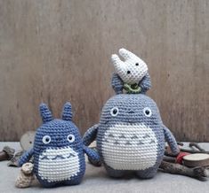 two crocheted totoro dolls sitting next to each other on the ground