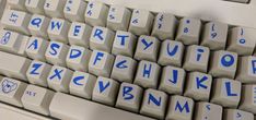 a computer keyboard with blue letters on it's keys and the bottom part of the keyboard is white