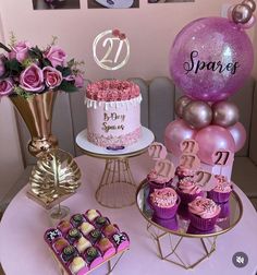 a table topped with cakes and cupcakes next to pink balloons in the shape of numbers