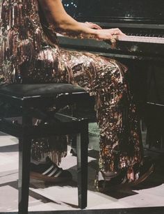 a woman sitting at a piano in front of a microphone and wearing a sequin dress