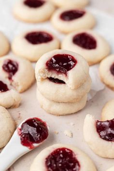 several cookies with jam on them and one has a bite taken out of the middle