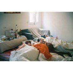 two people laying in bed with white sheets