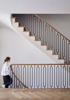 a woman in white shirt and black pants standing at the bottom of a stair case