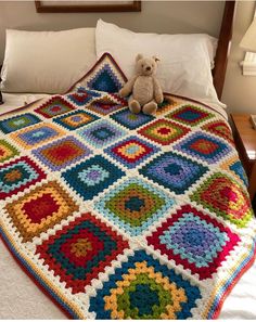 a teddy bear is sitting on top of a crocheted granny's afghan