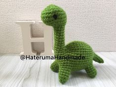 a crocheted green stuffed animal sitting next to a letter