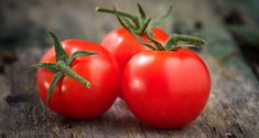 two red tomatoes sitting on top of a wooden table