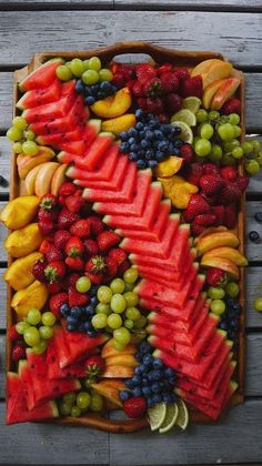 a platter filled with lots of fruit on top of a wooden table