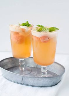 two glasses filled with drinks sitting on top of a metal tray