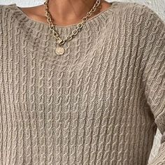 a woman wearing a sweater with a chain around her neck