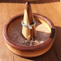 a wooden ring holder with two rings in it on top of a wood table next to other items